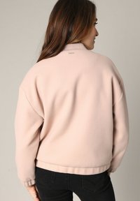 Roze fleece sweatshirt met een hoge kraag, verlaagde schouders en geribde mouwen. Gladde textuur en een subtiele merklogo op de achterkant.