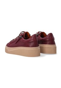 Rote Ledersneaker mit einer strukturierten beigen Plattformsohle, ausgestattet mit einer Schnürung und metallischen Hardware-Details.