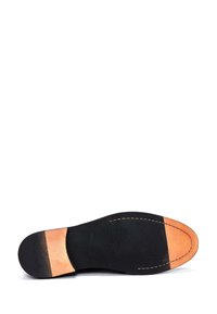 Semelle en caoutchouc noir avec une surface texturée et un accent de talon en cuir marron clair. Détails de couture le long du périmètre de la semelle.