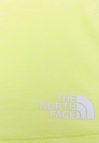 Leuchtend gelber Stoff mit weißem Logo, das geschwungene Akzente und fetten Text enthält, der den Markennamen "THE NORTH FACE" angibt.