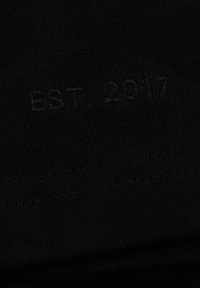 Black fabric with a fine ribbed texture; features the embossed text "EST. 2017" in a subtle, dark tone near the bottom edge.