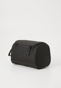 Bolso rectangular negro hecho de una tela duradera, con cierre de cremallera, bordes redondeados y un asa lateral para un transporte fácil.