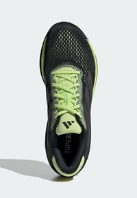 Černá sportovní bota s prodyšnou síťovanou špičkou, limetkově zelenými akcenty a textura spodní částí. Obsahuje zelené tkaničky a polstrovaný límec.