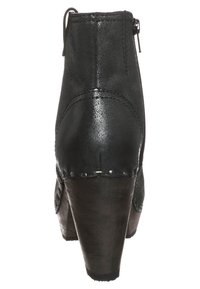 Bota de cuero negra hasta el tobillo con un acabado texturizado, tacón afilado, cierre de cremallera en el lado y tachuelas metálicas decorativas a lo largo de la suela.