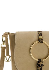 Beige Wildledertasche mit einem goldenen kreisförmigen Akzent und einem Leopardenmuster-Gurt. Enthält einen abnehmbaren Gurt für vielseitige Trageoptionen.