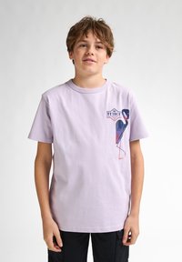 Lys lilla bomulds t-shirt med korte ærmer, der har et grafisk motiv af en fugl i blå og rød på venstre brystområde.