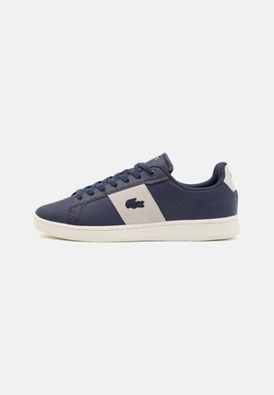 Sneaker blu navy con pelle testurizzata, dettagli crema e un patch con logo. Caratterizzato da una suola piatta e un design tradizionale con lacci.