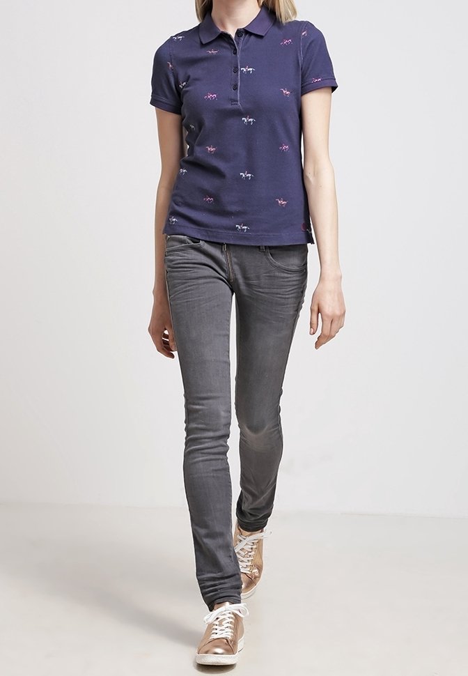 Marinblå polo med kort ärm och diskret djurmönster, i kombination med slim-fit grå jeans och metalliska sneakers för en avslappnad stil.