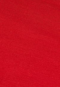 Tessuto rosso con una consistenza liscia e uniforme. Il tessuto presenta un motivo a maglia coerente, mostrando un colore vivace in tutta la sua superficie.