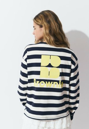 Striped long-sleeve shirt in navy and cream, featuring a yellow graphic with "Brownie" on the back. Cotton material with a relaxed fit.