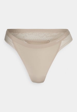 Beige thong underwear with a smooth front panel; lace detailing along the edges; logo printed on the waistband.
