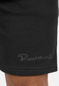 Zwarte katoenen shorts met een gladde textuur, een strakke pasvorm en een subtiele grijze "Reinsatt"-logo geborduurd nabij de zoom.