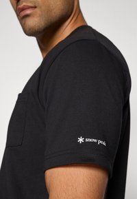 Black short-sleeve t-shirt made of cotton, featuring a chest pocket and a white "snow peak" logo on the sleeve. Smooth texture.