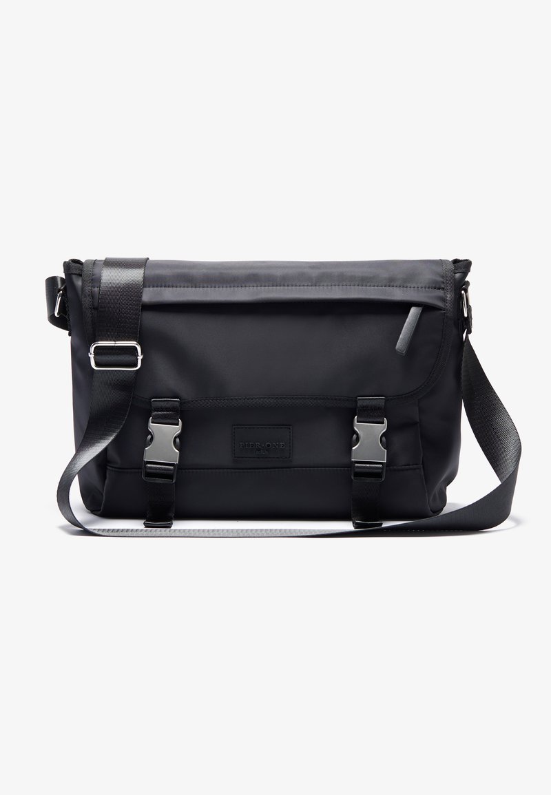 Crna messenger torba izrađena od izdržljive tkanine, s poklopcem zatvorenim s dva metalna kopčanja, dugim podesivim remenom i elegantnim dizajnom.