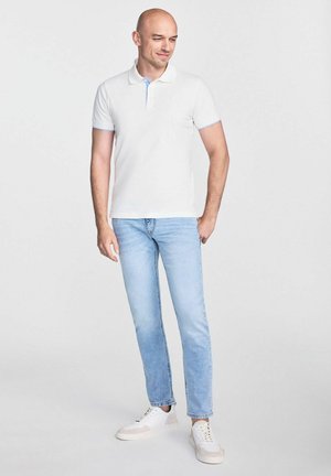 Biała koszulka polo z jasnoniebieskimi akcentami, zestawiona z jasnoniebieskimi dżinsami i białymi sneakersami. Casualowy krój, gładka tekstura, krótkie rękawy.