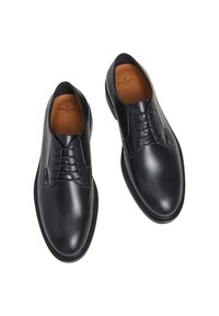 Scarpe in pelle nera con finitura liscia, design con lacci, punta arrotondata e cuciture in contrasto lungo la suola. Interno foderato.