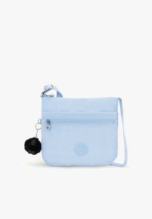 Bolso cruzado de color azul claro, fabricado en material suave, con un bolsillo delantero con cremallera, parche con logo y un charm de pelaje negro. Correa ajustable.