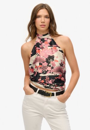 Satin halternek top met een bloemenontwerp in roze en zwart, met een getailleerde pasvorm, gedragen over witte broeken en een zwarte riem.