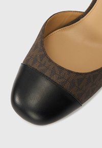 Καφέ μοτίβο φλατ παπούτσι με μαύρη στρογγυλή μύτη και μπεζ εσωτερική επένδυση σε λευκό φόντο.