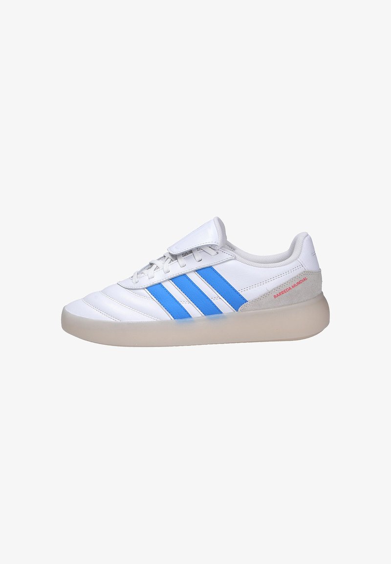 Baskets blanches avec des rayures bleues, semelle beige, devant lacé avec un rabat, et texte "BARREDA MUNDIAL" près du talon.