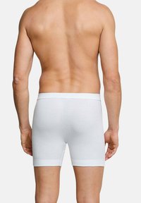 White cotton boxer shorts with a fitted design and elastic waistband, featuring a ribbed texture and no visible patterns or logos.