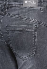 Mörkgrå denimjeans med en bakfickor som har knappstängning och subtila sömnadsdetaljer. Märket syns på midjebandet.
