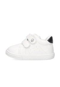 Zapatillas blancas para niños con dos correas de velcro, lados perforados y un acento en el talón negro. Suela de goma para tracción y soporte.