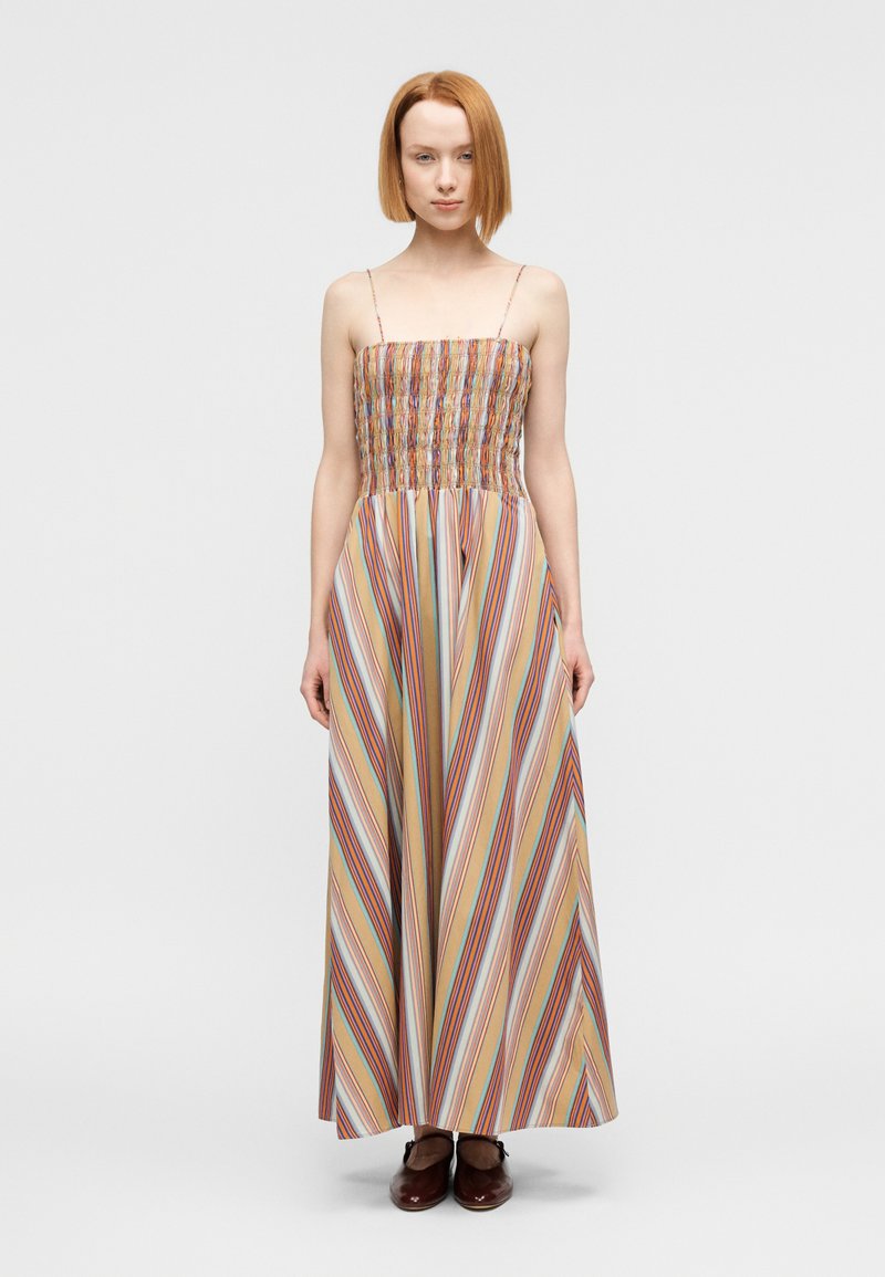 Μάξι φόρεμα με κορσάζ με σφηκοφωλι ά, λεπτές τιράντες και κάθετες πολύχρωμες ρίγες σε ελαφρύ ύφασμα. Φορεμένο με καφέ δερμάτινα παπούτσια.