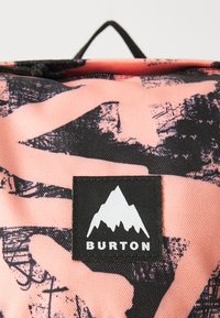 Zaino in tessuto rosa con motivi astratti neri, caratterizzato da un'etichetta nera rettangolare con una grafica di montagna bianca e il testo "BURTON".
