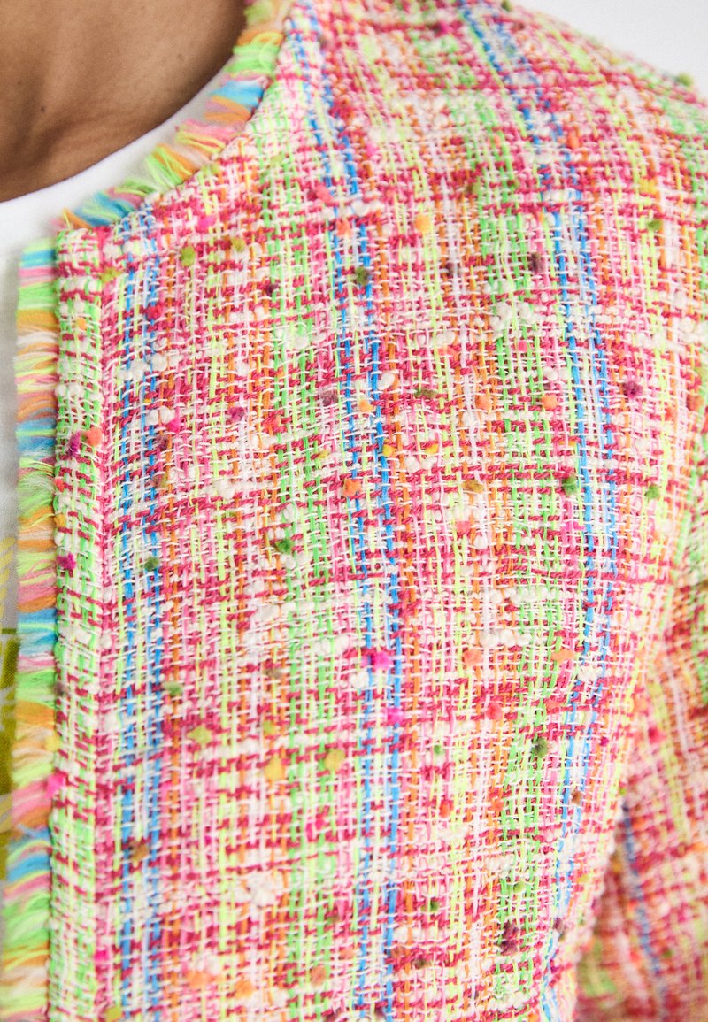 Mehrfarbige Tweedjacke mit einer strukturierten Webart in Pink, Grün und Blau, mit Fransenverzierungen entlang des Kragens und Saums.