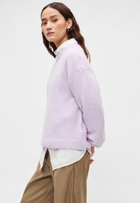 Μωβ υπερμεγέθη πουλόβερ με στρογγυλή λαιμόκοψη και ριμπ τελείωμα, συνδυασμένο με λευκό πουκάμισο με κουμπιά και χαλαρό καφέ παντελόνι. Απαλή υφή.