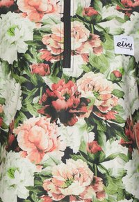 Kukallinen yläosa, jossa suuret pionin ja ruusun kuviot sävyissä vaaleanpunainen, punainen ja valkoinen, mustalla taustalla ja vetoketjuinen pääntie.