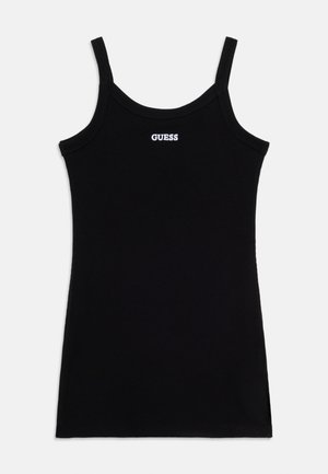 Svart ribbet singlet med tynne stropper og hvit "GUESS"-logo sentrert nær halslinningen, vist på en lys bakgrunn.