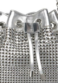 Srebrna torba na sznurkach wykonana z teksturowanego materiału, ozdobiona małymi, odbijającymi światło kamykami. Posiada metalowe okucia i dwa sznureczki do ściągania.