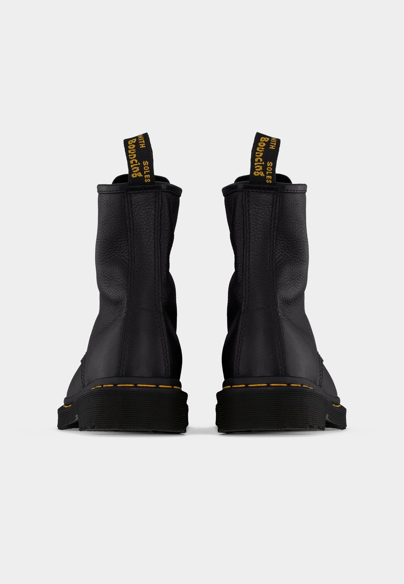 Zwarte leren enkellaarsjes met gele stiksels. Ze hebben een gestructureerd oppervlak en trek-lusjes met de tekst "bouncing soles" aan de achterkant.