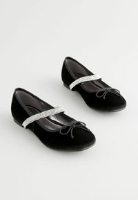 Schwarze Samt-Ballettschuhe mit einem Strassriemen, runder Zehenpartie, Schleifendetail an der Vorderseite und flacher Sohle. Glatte Innenauskleidung.