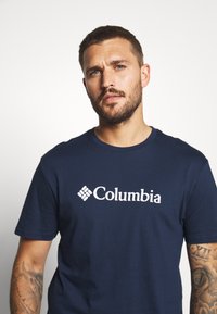 Men's navy blue cotton t-shirt featuring a white Columbia logo on the front. Short sleeves, round neckline, and smooth texture.