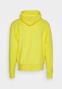 Ljusgul hoodie, blandning av bomull, har en mjuk textur, justerbar dragsko på huven och ribbade ärmslut med en avslappnad passform.