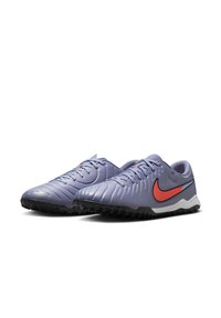 Purple synthetic soccer shoes with textured surface, red Nike swoosh, black outsole, and white midsole. Features lace-up closure and padded collar.