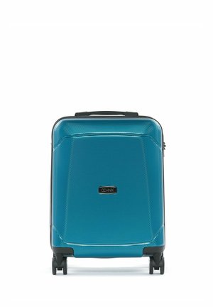 Twarda niebieska walizka kabinowa na czterech czarnych kółkach obrotowych i z górnym uchwytem, oznaczona prostokątną tabliczką z logo OCHNIK.