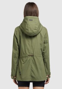 Giacca leggera verde con vita regolabile, cappuccio, polsini abbottonati e una patch con logo sul retro. Texture liscia, design informale.