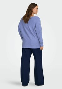 helehall sinine soonikkoes kampsun, millel on lõdvestunud istuvus ja pikad varrukad, kombineeritud tumesiniste laiade pükstega. Lihtne disain ilma nähtavate mustriteta.