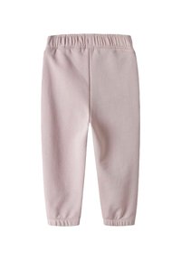 Lichtroze katoenen broek met een elastische tailleband, taps toelopende benen en manchetten. Gladde textuur en eenvoudig ontwerp, zonder extra patronen of details.