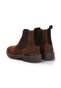 Botas Chelsea de ante marrón con paneles laterales elásticos y tiradores. Suelas de goma gruesa que proporcionan tracción. Textura suave con un acabado mate.