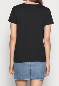 Svart kortärmad t-shirt med rund halsringning, kombinerad med en denimkjol. Tyget är slätt med en figurnära silhuett.