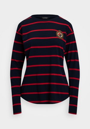 Camiseta de manga larga azul marino con rayas rojas horizontales y un cuello redondo, que presenta un emblema bordado en el pecho. Textura de tejido suave.