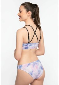 Sportinis liemenėlė ir bikinis su pasteliniu tinklelio raštu, kuriame dominuoja violetinė, rožinė ir mėlyna spalvos. Ypatybės: kryžminiai dirželiai ir patogus prigludimas.