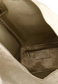 Guldmetallisk tote bag med tekstureret overflade, der har en indvendig lynlåslomme og kædedetalje. Rummelig design med bløde kanter.