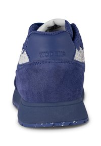 Sneaker blu scamosciato con upper testurizzato e accenti bianchi. Presenta un colletto imbottito e suola in gomma. Logo "WODEN" impresso sul tallone.