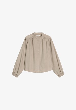 Beige Bluse mit langen Ärmeln aus weichem Stoff, hohem Kragen, Knopfleiste und Raffung an den Schultern und den Ärmelbündchen.